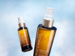site-industries-cosmetiques 天蓝色背景下是两个带白色瓶盖的 Moroccanoil 护理液棕色瓶子。其中一个瓶子直立，距离较近，而另一个瓶子倾斜，距离较远。