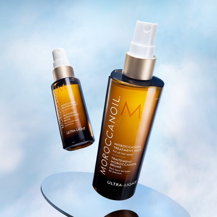 site-industries-cosmetiques Dois frascos castanhos de tratamento Moroccanoil com tampas brancas são mostrados contra um fundo azul-celeste. Um dos frascos está na vertical e mais próximo, enquanto o outro está inclinado e mais afastado.