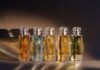 site-industries-cosmetics 博尔米奥利-路易吉（Bormioli Luigi）设计的五个带有金色标签和水晶瓶塞的玻璃香水瓶在暖色调灯光的映衬下排列成一排，每个瓶子都采用了受 Spoturno 启发的玻璃创新技术，并装有不同颜色的液体。.