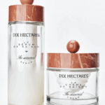 site-industries-cosmetiques Deux récipients en verre contenant des produits de soin de la peau Dix Hectares sont présentés sur une surface blanche. L'un est un grand flacon de sérum et l'autre un petit pot de crème. Les deux ont des couvercles à motifs de marbre et des étiquettes en texte noir.