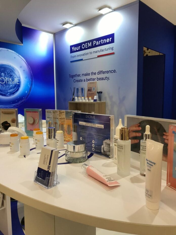 PHOTO-2025-09-29-10-17-15-1 site-industries-cosmetiques Stand de exposición en el que se presentan diversos productos cosméticos y para el cuidado de la piel en frascos, tarros y tubos, con paneles informativos. En el fondo, una pancarta azul y blanca presenta ALPOL Cosmétique como