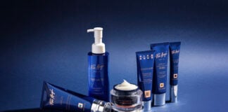 site-industries-cosmetiques Une gamme courte de six produits de soins dermo-cosmétiques bleus Pier Augé - flacons de lotion, pots de crème et tubes - est disposée sur une surface bleue avec un fond assorti. Un pot est ouvert, révélant un tourbillon de crème blanche.