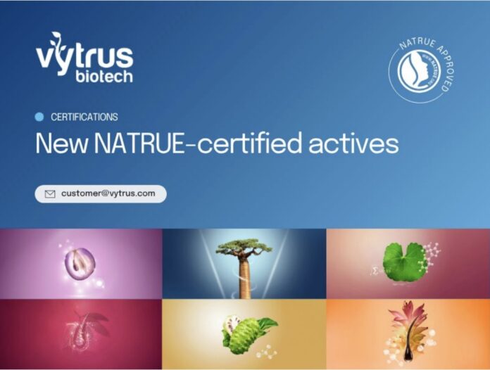 site-industries-cosmetiques Imagen promocional de Vytrus Biotech anunciando la nueva certificación Natrue para ingredientes cosméticos, con el logotipo de la empresa, la dirección de correo electrónico de contacto, el distintivo NATRUE Approved y seis pequeñas imágenes de ingredientes naturales sobre fondo azul.
