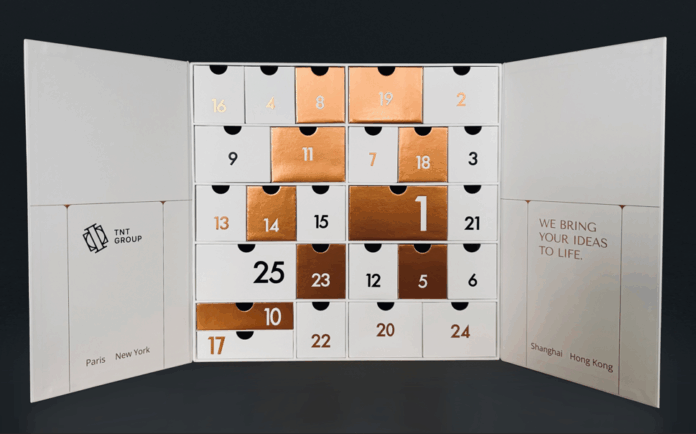 site-industries-cosmetiques Uma caixa de calendário do advento branca do Grupo TNT, com gavetas numeradas em cobre metálico e branco dispostas em grelha, demonstra a sua experiência em embalagens excepcionais. Os nomes das cidades estão indicados na parte inferior de cada aba.