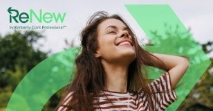 site-industries-cosmetiques 一位身着条纹衬衫、留着棕色长发的女士微笑着站在外面，闭着眼睛。左上角的绿色图案上印有 "ReNew by Kimberly-Clark Professional "字样。