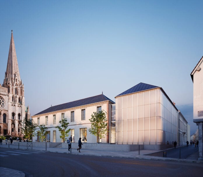 site-industries-cosmetiques A modern glass building and a traditional stone building stand side by side next to a historic stone church with a high spire, in France. As night falls, many people walk or stand on the cobbled area, reflecting the town's blend of heritage and cosmetic innovation.