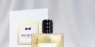 site-industries-cosmetiques 一个贴有 "Dog De Lux Grasse "标签的透明玻璃香水瓶，黑色瓶盖，放置在一个贴有相同标签的白色和金色相匹配的盒子前，背景淡雅而模糊。.