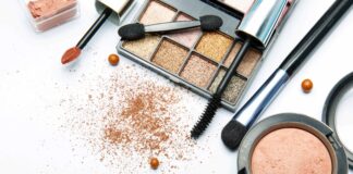 site-industries-cosmetiques 在白色表面上散落着各种化妆产品，包括眼影盘、口红涂抹器、腮红盒、睫毛膏棒、粉饼和化妆粉。.