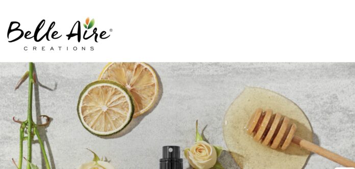 site-industries-cosmetiques Le logo de Belle Aire Creations au-dessus d'une présentation à plat comprenant des tranches d'agrumes séchées, des roses blanches, un flacon pulvérisateur noir et une cuillère à miel dans du miel sur une surface gris clair souligne leur forte présence nord-américaine.