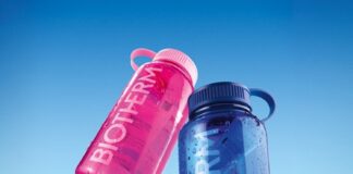 site-industries-cosmetiques Trois bouteilles d'eau en plastique réutilisables sont représentées sur un fond bleu. Les bouteilles sont roses, bleues et sarcelles, chacune avec une poignée et le mot "BIOTHERM" imprimé en grandes lettres blanches sur le côté.