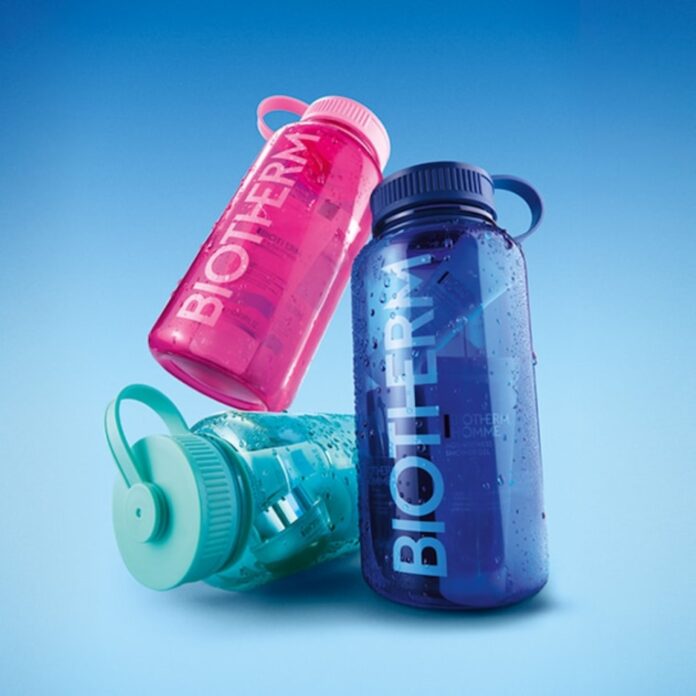 site-industries-cosmetiques Three reusable plastic water bottles are shown on a blue background. The bottles are pink, blue and teal, each with a handle and the word 