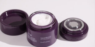 site-industries-cosmetiques 打开一个标有 "Vagheggi Phytocosmetic "的紫色罐子，里面装有白色面霜，盖子和一个圆形涂抹器放在白色表面上。.