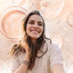 Nutricosmetics By Lallemand to Shine from the Inside Out site-industries-cosmetiques A young woman with long brown hair smiles against a background of Petri dishes and abstract scientific shapes, reflecting Nutricosmetics' philosophy of shining from within in soft shades of peach and beige.