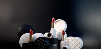 site-industries-cosmetiques 三支红色尖端的口红垂直摆放在各种黑白相间的圆形容器和盖子中，所有容器和盖子都摆放在深色背景的深色表面上。.