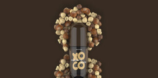 site-industries-cosmetiques 一个标有 "Yoco榛子酱 "的瓶子竖放在中央，周围是一圈棕色背景上的完整榛子核。.