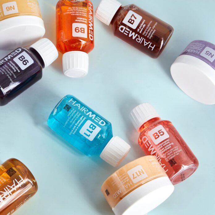 site-industries-cosmetiques Varias botellas y tarros de colores etiquetados con letras y números, como B1, B5 y N7, están dispuestos sobre una superficie azul claro. En las etiquetas se puede leer 