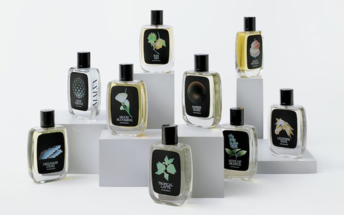 site-industries-cosmetiques Diez frascos de perfume con diferentes etiquetas ilustradas están dispuestos sobre plataformas blancas de diferentes alturas sobre un fondo blanco. Cada frasco tiene un diseño único que representa su fragancia.