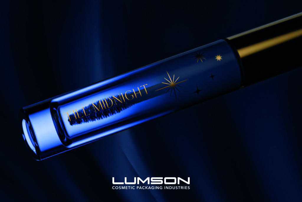 site-industries-cosmetiques Grande plano de um rímel azul num tubo de vidro com "THE MIDNIGHT" e estrelas impressas. O fundo é azul escuro e o logótipo da Lumson Cosmetic Packaging Industries aparece na parte inferior.