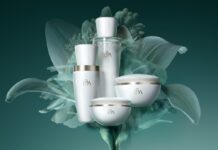 site-industries-cosmetiques Quatre contenants de produits de soins blancs avec des accents argentés, étiquetés "LBA", sont disposés devant une fleur verte translucide sur un fond sarcelle. Il s'agit de bouteilles et de pots ronds.