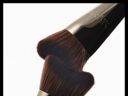 site-industries-cosmetiques 在纯白背景上，两把深棕色刷毛、金属柄的化妆刷面对面、成一定角度放置，刷毛几乎相触。.