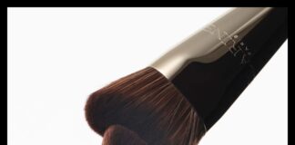 site-industries-cosmetiques 在纯白背景上，两把深棕色刷毛、金属柄的化妆刷面对面、成一定角度放置，刷毛几乎相触。.