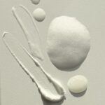 site-industries-cosmetiques 在发光表面上排列着各种质地的护肤品或化妆品，包括不同形状和大小的奶油状、泡沫状和凝胶状物质。.