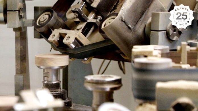 site-industries-cosmetiques Vue rapprochée d'une machine à bois automatisée façonnant des pièces de bois circulaires, avec un emblème 