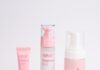site-industries-cosmetiques 在纯白背景的白色圆形展示架上摆放着五件粉色和白色的 Arval Collageniques 护肤产品，包括两个罐子、一个泵瓶、一个管子和一个泡沫分配器。.