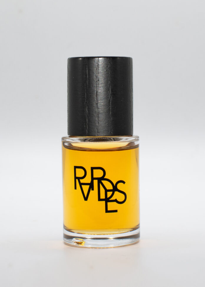 site-industries-cosmetiques A small transparent glass bottle filled with a yellow liquid, topped with a black cork. The bottle bears the word 