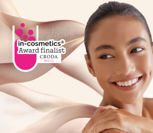 site-industries-cosmetiques Uma mulher com uma pele radiante e estruturada sorri e olha para o lado. O texto sobreposto diz: "finalista do prémio in-cosmetics CRODA Beauty". No fundo, formas abstractas cor-de-rosa.