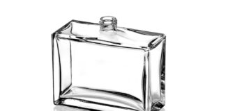 site-industries-cosmetiques Uma garrafa de vidro transparente, retangular, com um pequeno gargalo roscado no topo, colocada verticalmente sobre uma superfície branca reflectora. A garrafa está vazia e tem superfícies lisas e planas.