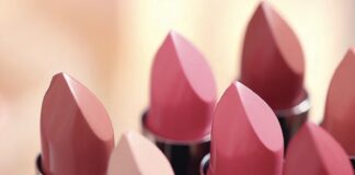 site-industries-cosmetiques Plusieurs tubes de rouge à lèvres de différentes nuances de rose et de nude sont disposés les uns à côté des autres, les extrémités pointées vers le haut. L'arrière-plan est légèrement flou.
