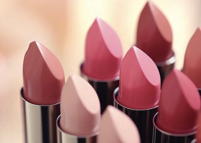 site-industries-cosmetiques Plusieurs tubes de rouge à lèvres de différentes nuances de rose et de nude sont disposés les uns à côté des autres, les extrémités pointées vers le haut. L'arrière-plan est légèrement flou.