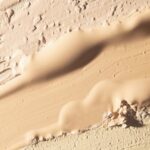site-industries-cosmetiques Um grande plano sobre vários tons de bege e castanho claro da base «Essence Nude» da MPlus Cosmetics, aplicados e esbatidos para formar camadas texturadas e irregulares — uma antecipação das tendências do salão MakeUp in Paris 2026.