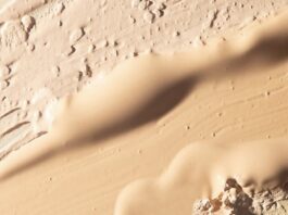 site-industries-cosmetiques Gros plan sur plusieurs nuances de beige et de brun clair du fond de teint « Essence Nude » de MPlus Cosmetics, appliquées et estompées pour former des couches texturées et irrégulières — une anticipation des tendances du salon MakeUp in Paris 2026.