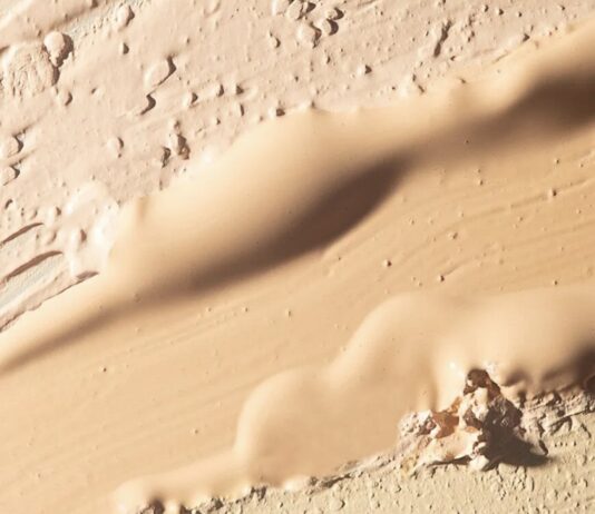 site-industries-cosmetiques Gros plan sur plusieurs nuances de beige et de brun clair du fond de teint « Essence Nude » de MPlus Cosmetics, appliquées et estompées pour former des couches texturées et irrégulières — une anticipation des tendances du salon MakeUp in Paris 2026.