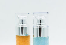 D.I.V.A.S., Technature's Technology Pushing the Boundaries of Formulation site-industries-cosmetiques Two cylindrical glass bottles with pump dispensers, one filled with orange gel beads and the other with blue gel beads, stand upright on a white background - perfect for storing CSR products in style.