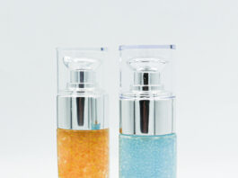 site-industries-cosmetiques 两个带泵分配器的圆柱形玻璃瓶，一个装满了橙色凝胶珠，另一个装满了蓝色凝胶珠，在白色背景的衬托下直立起来，非常适合存放 CSR 产品。.