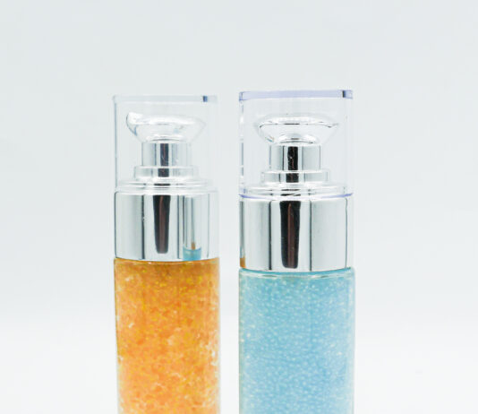 site-industries-cosmetiques Deux flacons cylindriques en verre avec distributeurs à pompe, l'un rempli de billes de gel orange et l'autre de billes de gel bleues, se tiennent debout sur un fond blanc - parfaits pour stocker les produits RSE avec style.