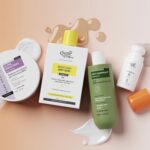 L’Oréal prend une participation majoritaire dans Innovist en Inde site-industries-cosmetiques Une composition « flat lay » de cinq produits de soin pour la peau et les cheveux, comprenant des crèmes, un gel douche, un shampoing et un flacon muni d’un bouchon orange, disposés sur une surface rose, avec des traces de produit et des éclaboussures de liquide tout autour.
