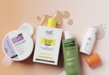 site-industries-cosmetiques A «flat lay» arrangement of five skin and hair care products, including creams, a shower gel, a shampoo, and a bottle with an orange cap, arranged on a pink surface, with traces of product and splashes of liquid all around.