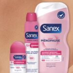 Sanex lanza Derma Menopausia, una rutina centrada en la piel y las sensaciones de calor site-industries-cosmetiques Se presentan tres productos de la gama Sanex Derma Care+ Menopause: un desodorante en bola, un desodorante en spray y un frasco de gel de ducha, todos ellos con un envase rosa y blanco, que destaca sobre un fondo con un primer plano de piel.