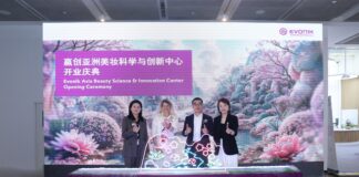 site-industries-cosmetiques Quatro pessoas estão de pé atrás de um pódio decorado com luzes na cerimónia de abertura do Evonik Asia Beauty Science & Innovation Center, em frente a uma exposição de flores e a um cartaz com o nome do evento em inglês e chinês.