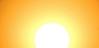 The FDA Approves BASF's Bemotrizinol UV Filter site-industries-cosmetiques A dazzling white sun occupies the center of the image, radiating yellow and orange light that gradually fades toward the edges, creating a warm and luminous effect against a clear sky.