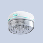 Nuon Medical 将药剂注入给药器中 site-industries-cosmetiques 一款Nuon Medical品牌的电子头皮按摩仪,颜色为白色和浅青绿色,配有透明底座,底座上布满多个硅胶按摩突起,展示在纯浅灰色背景上。.