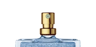 site-industries-cosmetiques Un frasco de perfume cuadrado de cristal, provisto de un pulverizador dorado y relleno de perlas de gel azules creadas mediante la tecnología de encapsulación Microcaps, destaca sobre un fondo blanco liso.