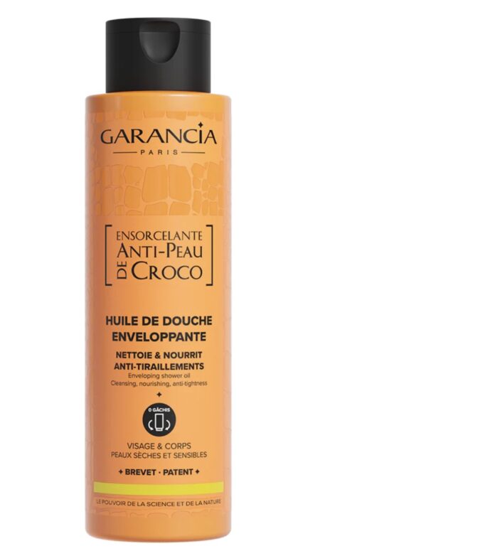 site-industries-cosmetiques Un frasco naranja de aceite de ducha «Anti-Peau de Croco» de Garancia Paris, destinado a pieles secas y sensibles, cuya etiqueta está redactada en francés. El frasco tiene un tapón negro y contiene 400 ml de producto para el rostro y el cuerpo.